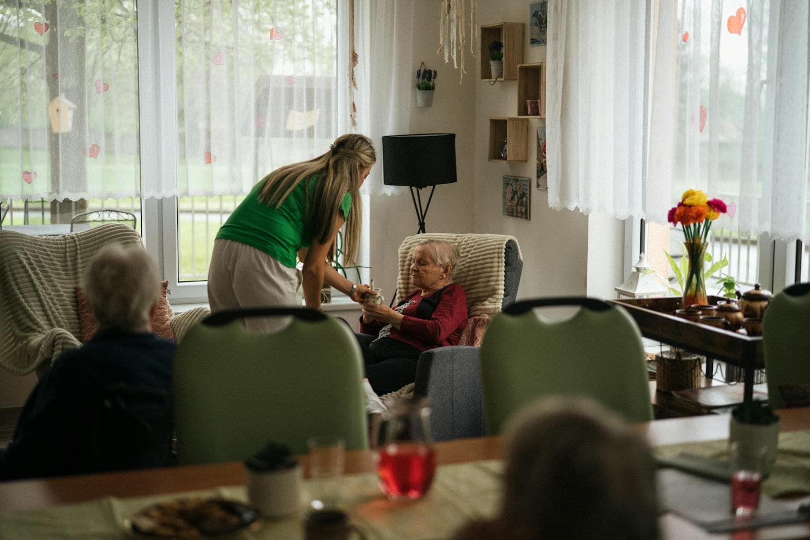 A caregiver assists elderly women with tea — afternoon care shift in 24-hour home care.
